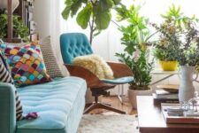 a mid-century modern living room with a turquoise sofa and bright pillows, a blue chair and a coffee table, potted plants