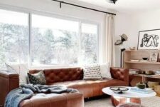 a mid-century modern neutral living room with a brown leather corner sofa and matching Moroccan poufs