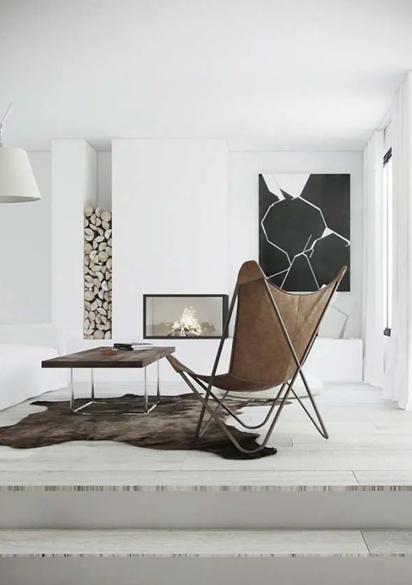 a minimal space with a built in fireplace, firewood, a black and white artwork, a stained table and a leather butterfly chair