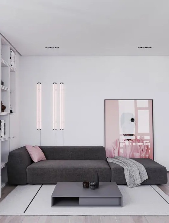 a minimalist living room with a graphite grey low sofa, a coffee table, a pink artwork and pink neon lights, a pink sofa