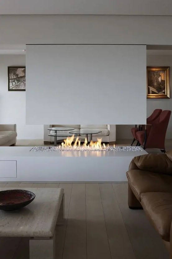 a minimalist living room with a whie ethanol fireplace, a brown leather fireplace, a low coffee table and artworks