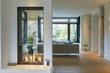 a minimalist white double-sided fireplace with an additional seat by its side is a cool idea to enjoy fire from all sides
