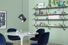 a mint green dining rom with a shelving unit, a round table and navy chairs, a round rug and a black pendant lamp