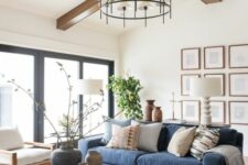 a modern farmhouse living room with a navy sofa, a round coffee table, neutral chairs, printed pillows and a grid gallery wall