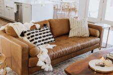 a modern farmhouse living room with a tan leather couch and a navy velvet one, a living edge table and printed rugs is wow