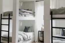 a modern kids’ room with built-in bunk beds, black ladders, a mirror cabinet, a printed rug and neutral bedding