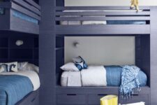 a modern kids’ room with grey bunk beds, blue and white bedding, a striped rug, some toys is a stylish space to be in