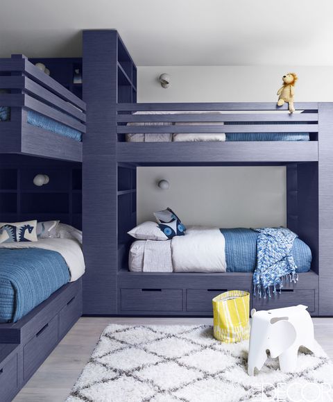 a modern kids' room with grey bunk beds, blue and white bedding, a striped rug, some toys is a stylish space to be in