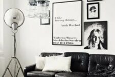 a monochromatic Scandi living room with a black leather couch, a gallery wlal, pendant jar lamps and a coffee table