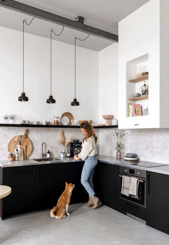 a monochromatic kitchen with black cabinets, an open black shelf instead of upper cabinets, a concrete countertop and a grey tile backsplash