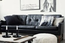 a monochromatic living room with a black leather couch, a gallery wall, an industrial coffee table on casters and a white leather pouf