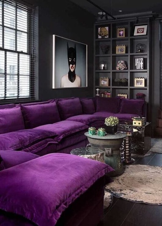a moody contemporary living room done in black and graphite grey, a built-in shelf for displaying, a purple sectional and a statement artwork