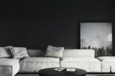 a moody living room with black walls and a ceiling, low grey seating furniture and black round walls for monochrome lovers
