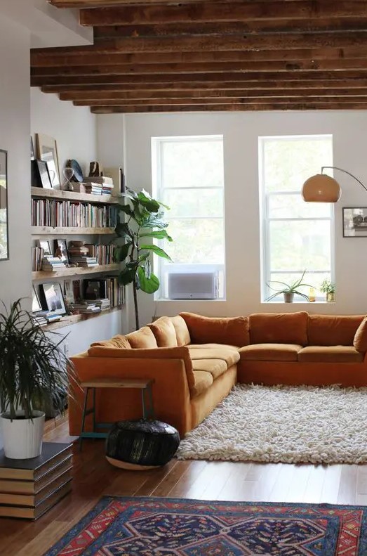 a mustard colored L shaped sofa brings warmth to the space and matches the rustic feel