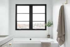 a neutral contemporary bathroom with a black casement window, a neutral console, a built-in bathtub, a marble hex tile floor