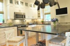 a neutral farmhouse kitchen with flat panel and shaker cabinets, a large kitchen island with a built-in dog crate inside