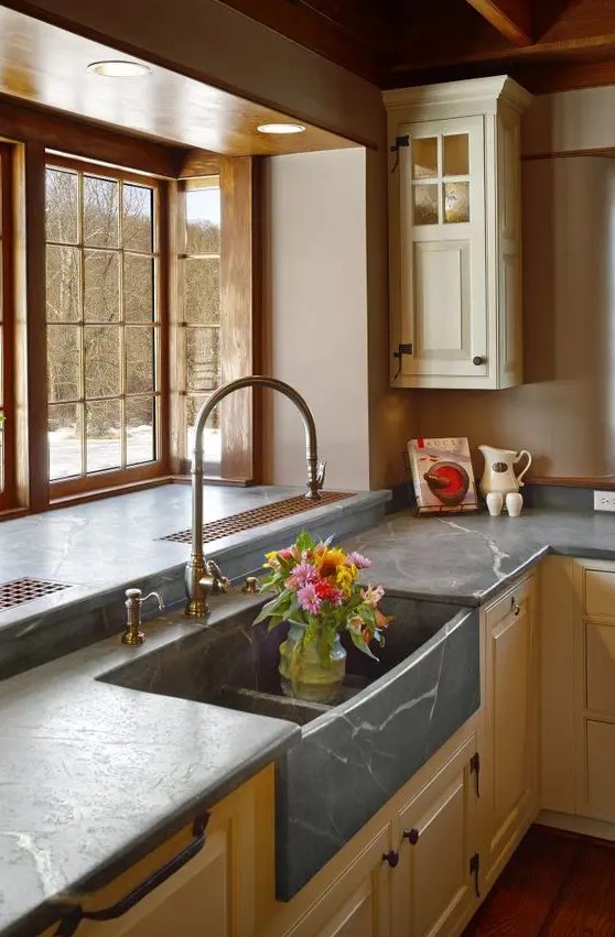 a neutral farmhouse kitchen with shaker cabinets, grey soapstone countertops and a bay window is adorable
