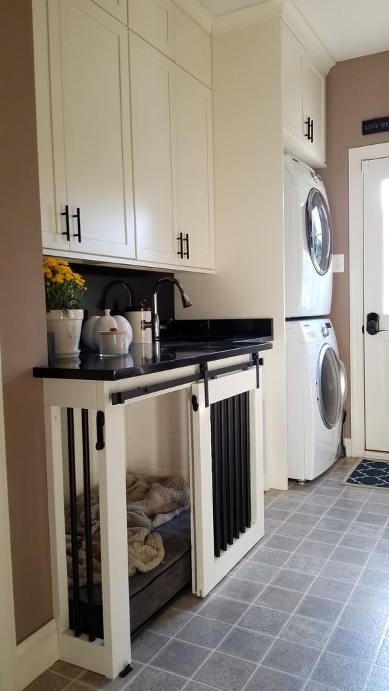 a neutral farmhouse laundry room with a built-in dog crate with a sliding door that is inside a cabinet