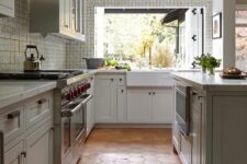 a neutral kitchen with shaker cabinets,  large kitchen island, white stone countertops, a pass through window and a terracotta tile floor