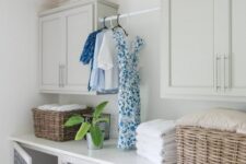 a neutral laundry room with shaker style cabinets, two built-in dog crates with blue pillows to keep your pets safe