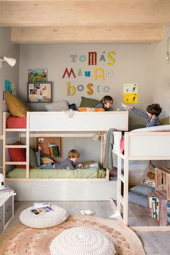 a pretty kids' room with multiple bunk beds, muted color bedding, a jute rug, some colorful decor