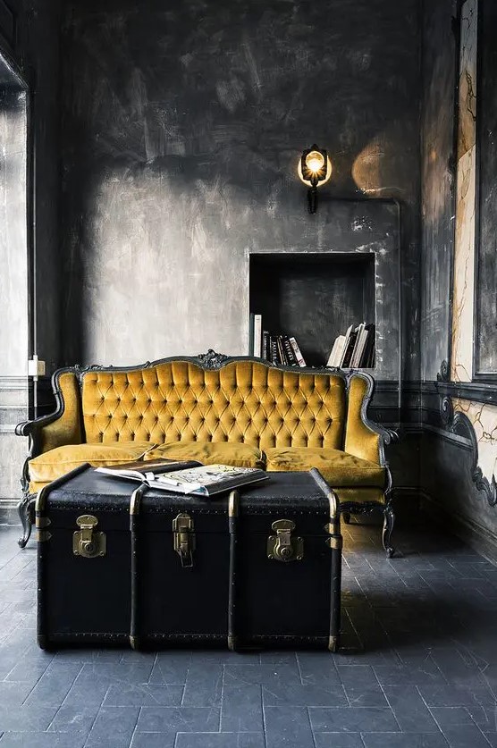 a refined and moody living room highlighted with a large black vintage trunk as a coffee table