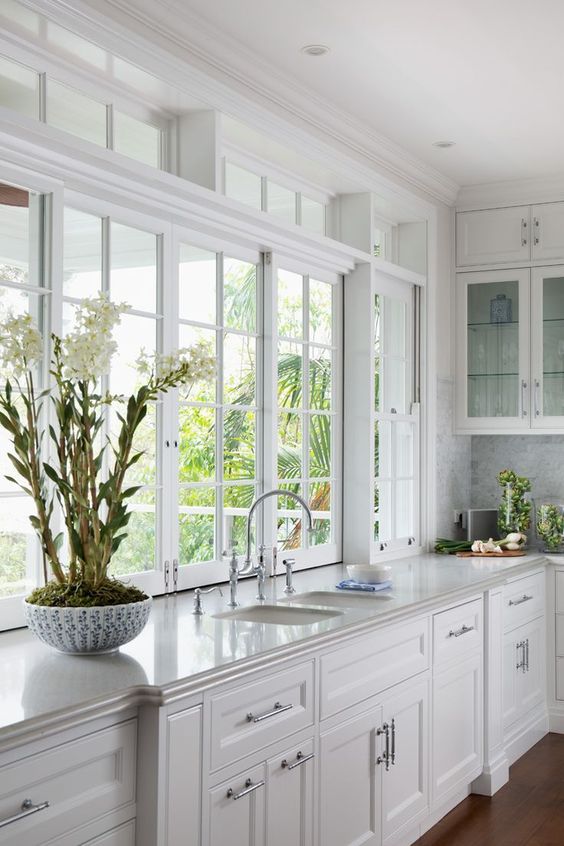 a refined white kitchen with shaker cabinets, casement and clerestory windows and a lot of light coming in