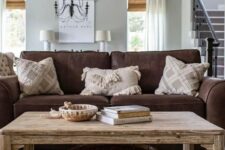 a rustic living room with a brown sofa, a rustic coffee table with decor, printed pillows is a stylish and cool space to be in