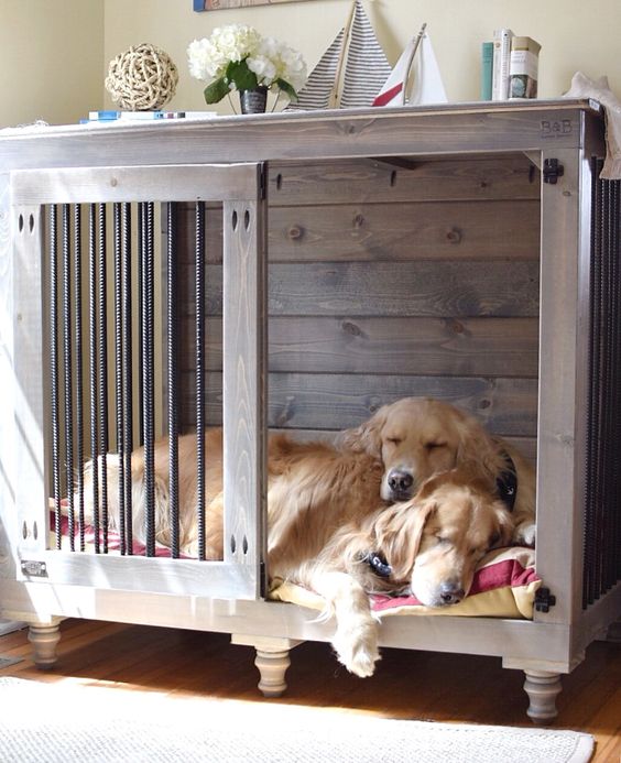 a rustic stained dog crate for two, with a large pillow inside and some decor as it doubles as a console table