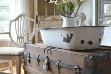 a rustic trunk works as a side table and a storage item in this vintage cottage interior