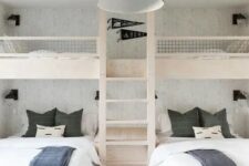 a simple and contrasting kids’ room with built-in bunk beds with white and graphite grey bedding, a ladder and a black pendant lamp