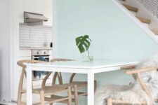 a small Scandi dining nook with a pastel mint wall, a white table and stained chairs, a black pendant lamp is a cool space