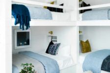 a small and cool coastal kids’ room with multiple bunk beds, neutral and printed bedding, a striped rug, woven baskets