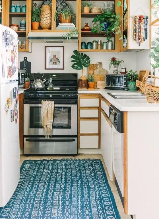 a small and lovely kitchen with white and stained open cabinets that are used for displaying dishes, jars and potted plants