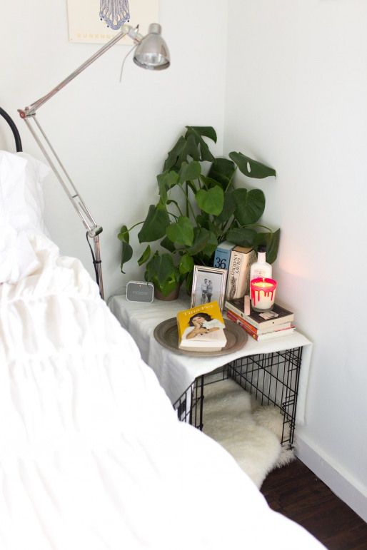 a small dog crate that doubles as a nightstand, with greenery, candles and some decor on top is a great idea