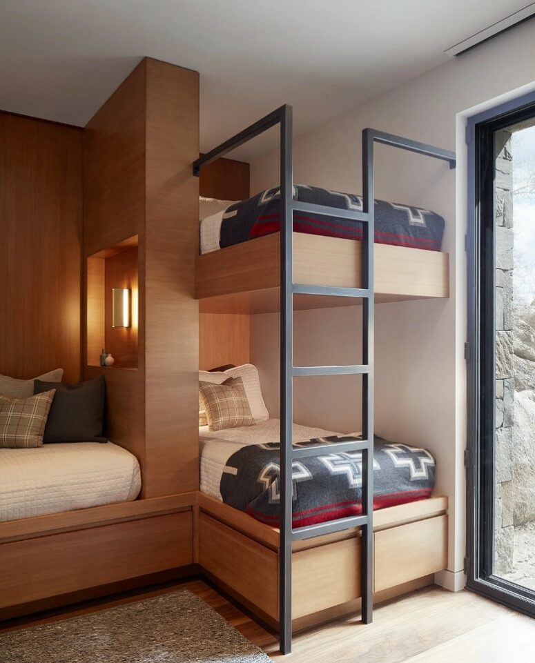 a small kids' bedroom with multiple bunk beds, printed bedding, a metal ladder and an entrance to the garden