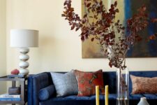 a sophisticated boho living room with a navy sofa, a bold printed rug, a hex glass coffee table and some lamps