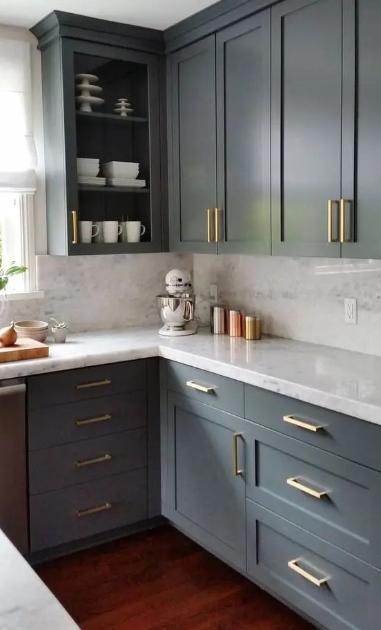 a sophisticated grey kitchen with shaker and open cabinets, white countertops and a backsplash, gold handles