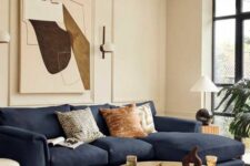 a sophisticated living room with trim on the walls, a navy sectional, a round coffee table and an abstract artwork