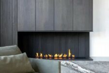 a sophisticated minimalist space with a dark wood fireplace and a grey marble slab, a grey low chair