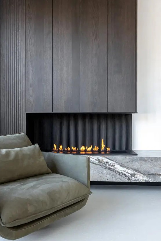 a sophisticated minimalist space with a dark wood fireplace and a grey marble slab, a grey low chair
