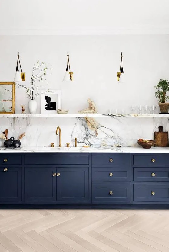 a sophisticated navy kitchen with shaker cabinets, a white marble backsplash, countertops and a ledge for displaying various stuff