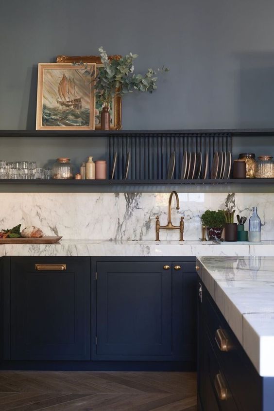 a sophisticated navy kitchen with shaker cabinets, open shelves for storage, white marble countertops and a backsplash and artwork