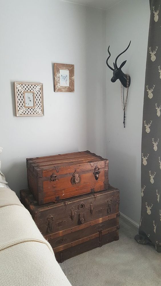 a stack of vintage stained chests as an alternative to a usual nightstand, it adds a cozy rustic feel to the bedroom
