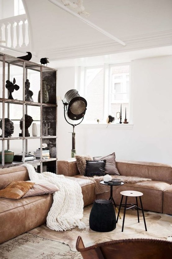 a stylish living room with a brown low sofa, small side tables, a large storage unit and some lamps