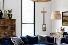 a stylish living room with a navy sofa, a black coffee table with drawers, a stained vintage file cabinet, some art and pendant lamps is a cool example of eclectics