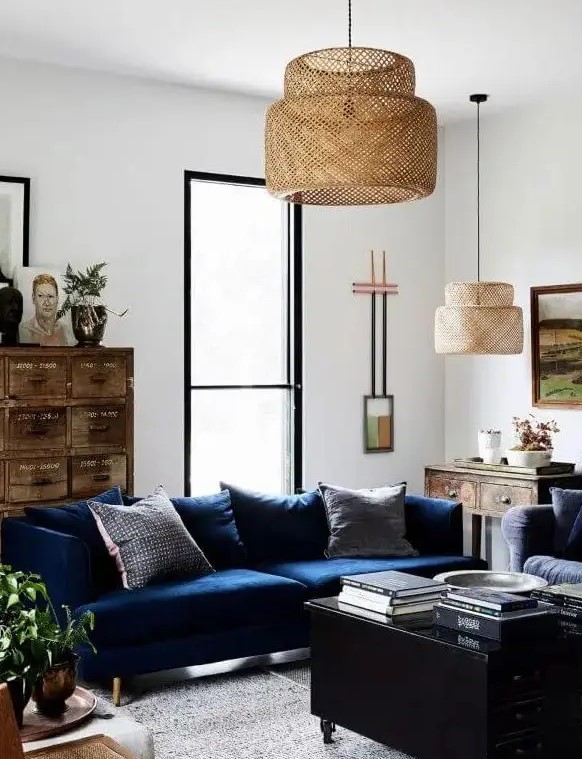 a stylish living room with a navy sofa, a black coffee table with drawers, a stained vintage file cabinet, some art and pendant lamps is a cool example of eclectics