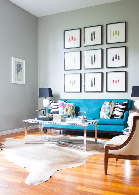 a stylish living room with a turquoise sofa, a gallery wall, a coffee table and rug is a chic and refined space