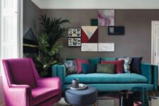 a stylish living room with grey walls, a turquoise sofa and a hot pink chair, a colorful gallery wall and a statement plant