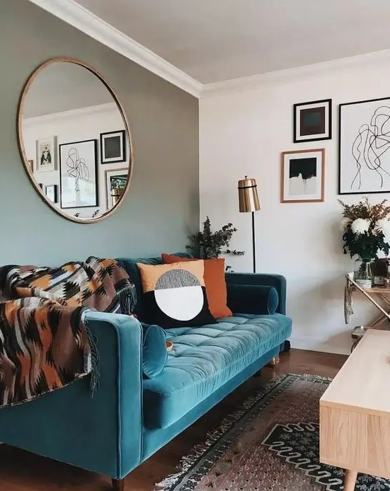 a stylish mid-century modern living room with a grey accent wall, a turquoise sofa, printed textiles and a monochromatic gallery wall